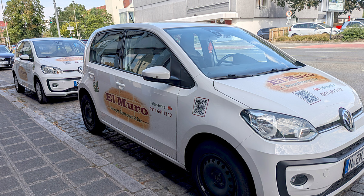 Zwei beschriftete VW Up Fahrzeuge von El Muro vor dem Restaurant in Nürnberg.